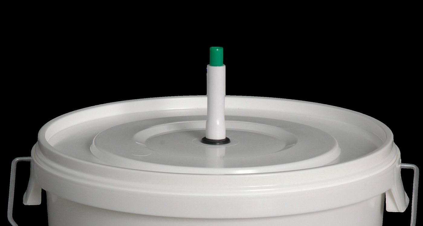 A homebrew fermenting pail fitted with an airlock — the simple sealed vessel in which pitched yeast quietly turns wort into beer.