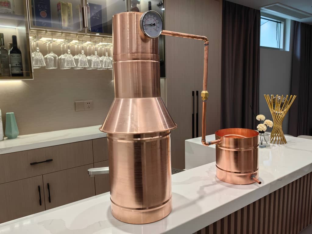 The Distillery Network mini copper pot still — full-copper construction, hand-built in Manchester, NH, lifetime warranty (reference only, vendor copyright)